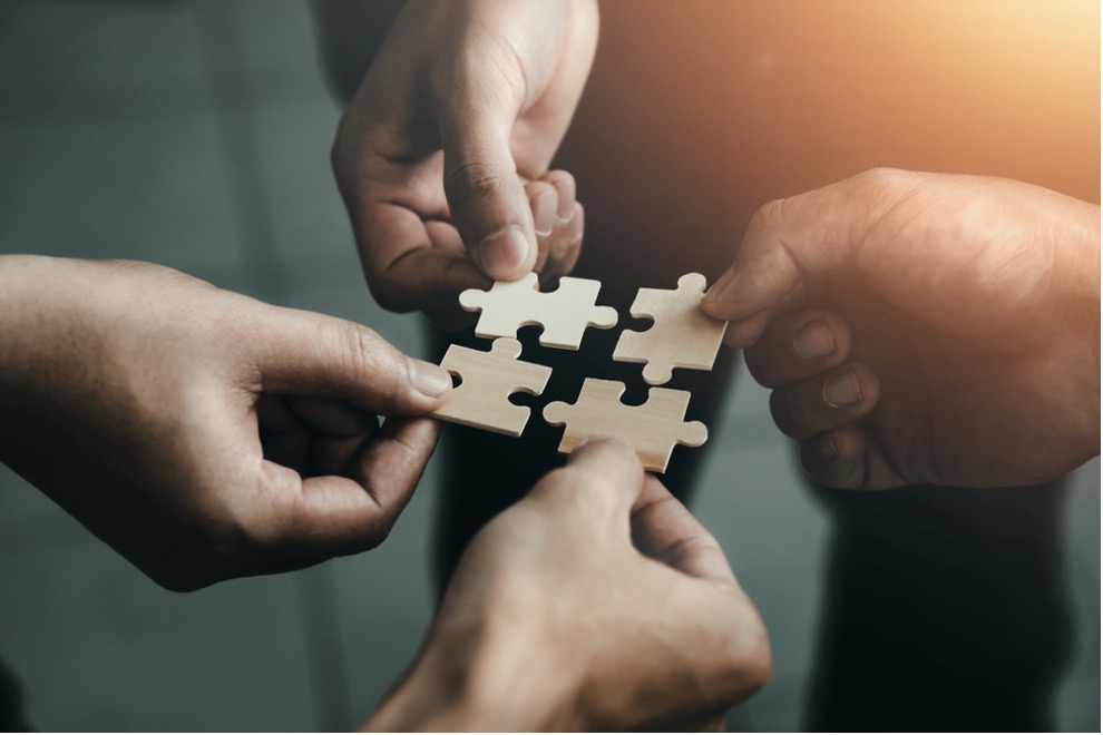 A group of hands holding a puzzle piece