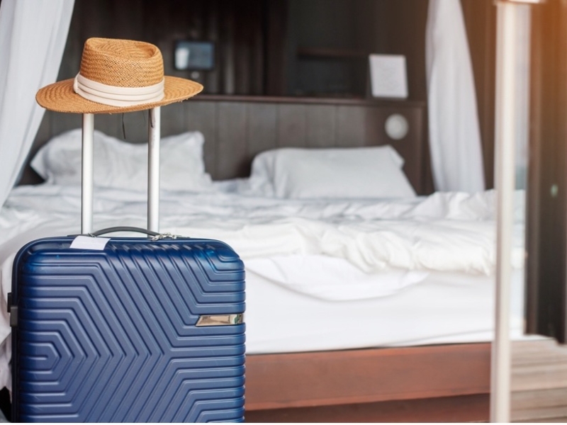 A blue suitcase with a hat on top of it