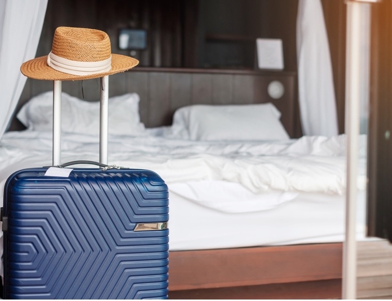 A blue suitcase with a hat on top of it