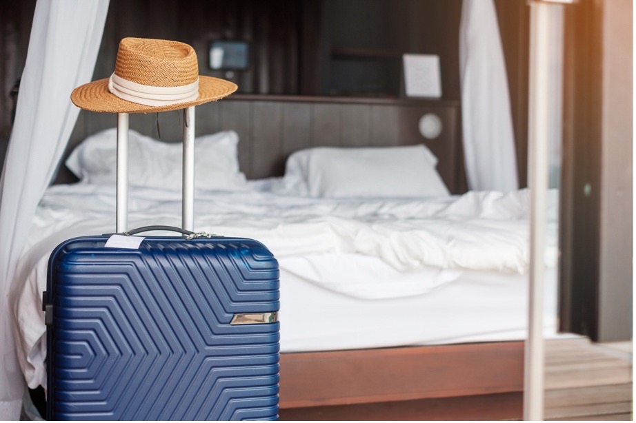 A blue suitcase with a hat on top of it