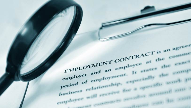 Closeup of employment contract on a clipboard with a magnifying glass up-close